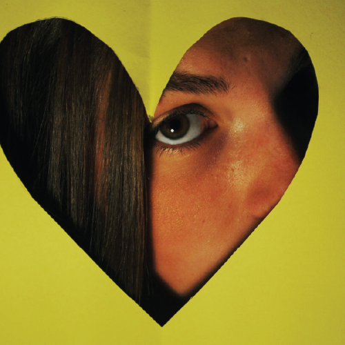 woman looking through a paper cutout of a heart