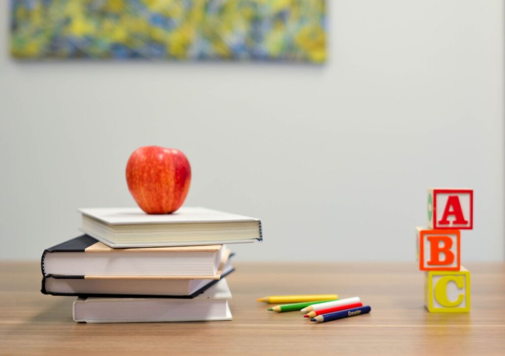 school books, ABC blocks, pencils, and apple on a table