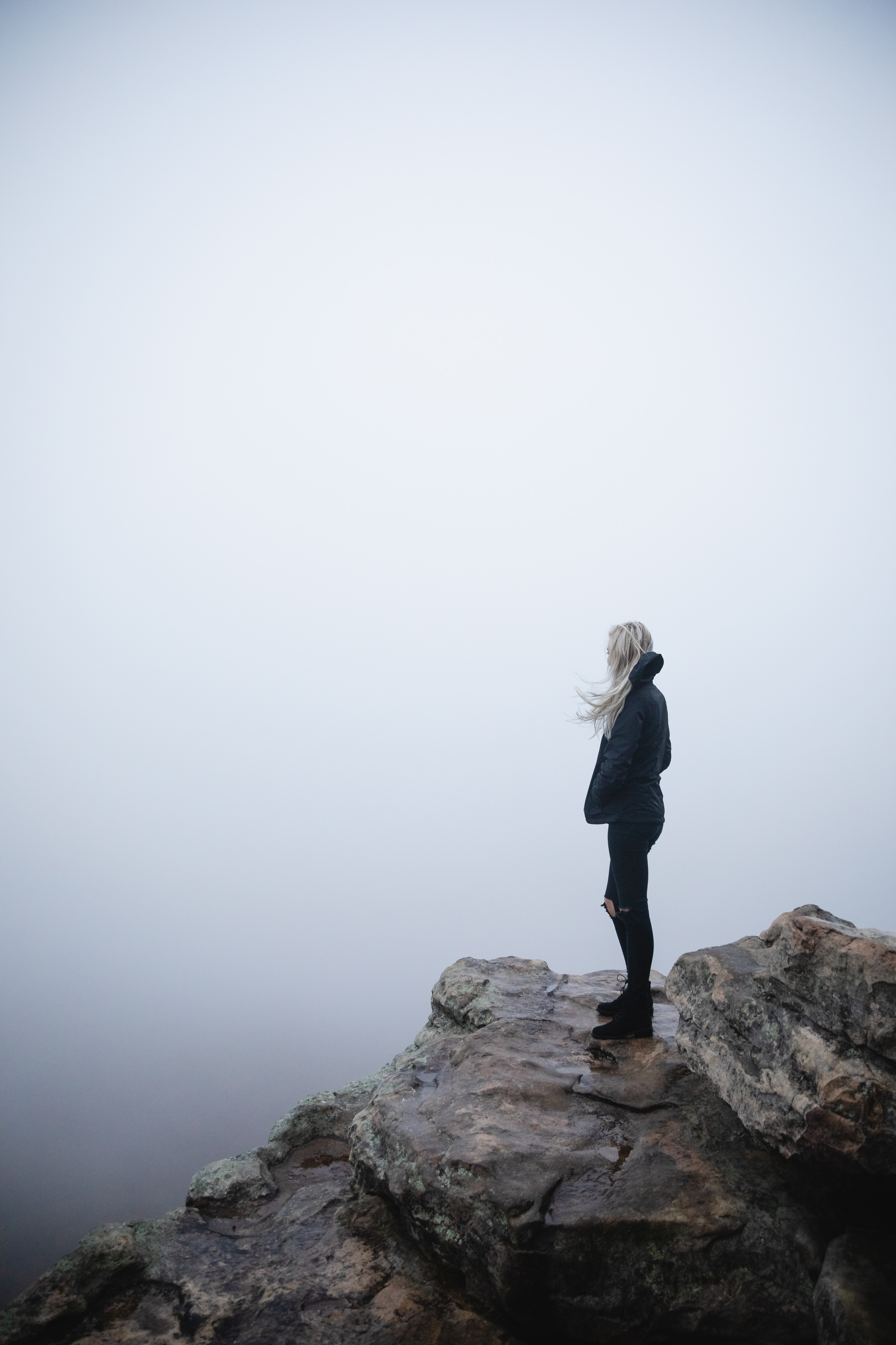 woman standing on rock with mist and fog in background